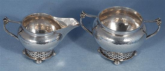 A George V planished silver Arts & Crafts sugar bowl and cream jug, by Albert Edward Jones, jug height 82mm, weight 10.3oz/321grms.